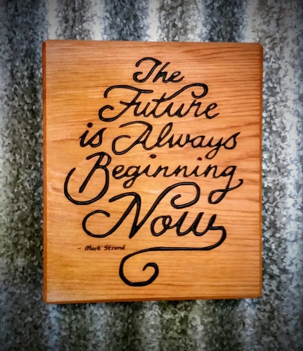 Front view of engraved wood quote magnet reads the future is always beginning now by mark strand