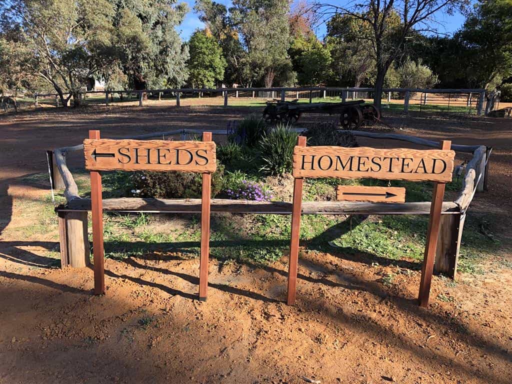 An example of some directional signs made from Cedar with rustic edges and arrows directing customers in a car park with a country setting scene behind. SHEDS pointing left and HOMESTEAD pointing right