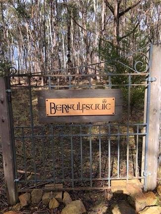 victorian ash sign hanging on gate reads bernulfsuuic (restaurant logo)