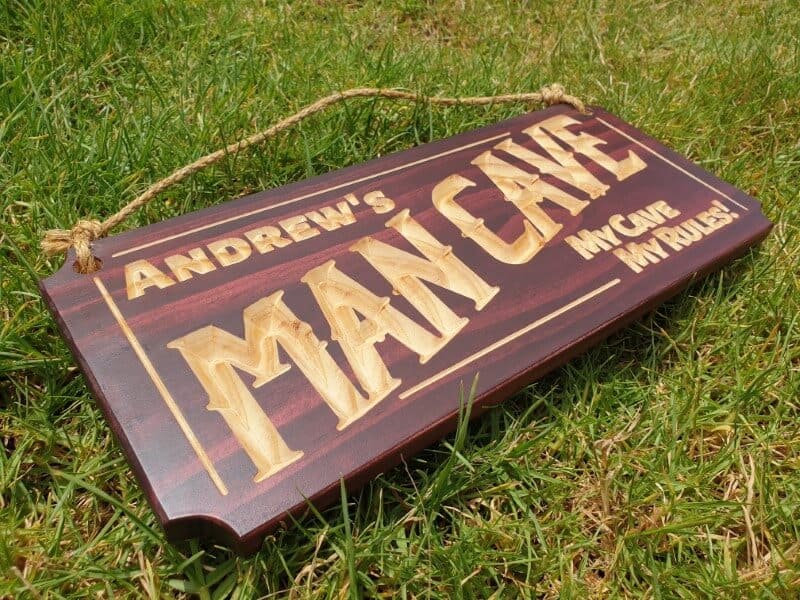 man cave sign Andrews my cave my rules laying on grass with hemp rope and mahogany stain