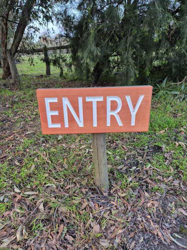 caravan park entry sign cedar with white painted lettering high visibility from road