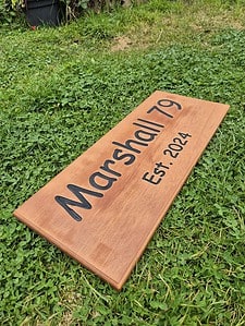 house name sign made from Cedar with carved out lettering painted black showing established date on second line of text