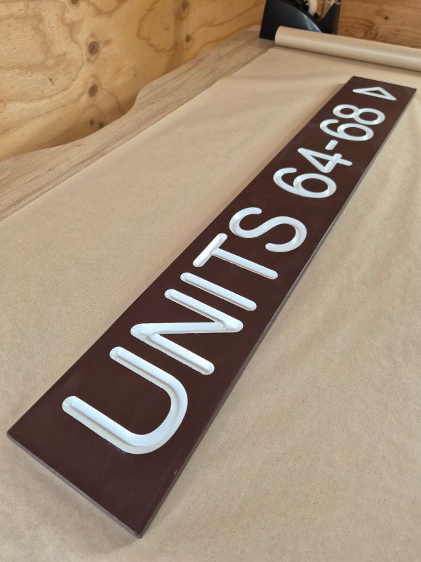 sign for units with white painted carved out lettering on a mission brown painted sign