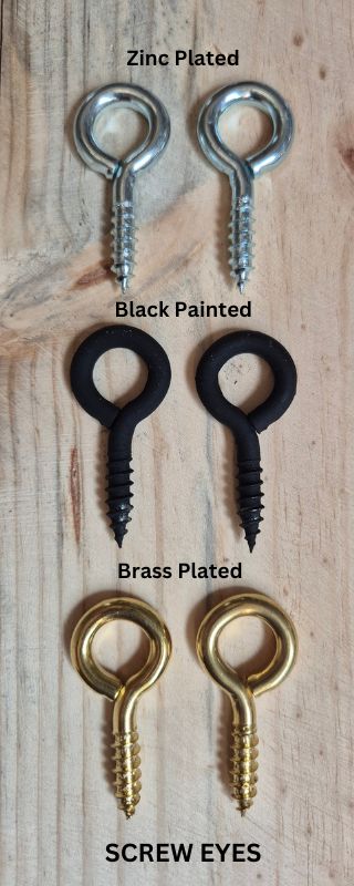 a selection of screw eyes on a wooden workbench top showing three versions zinc plated black painted or brass plated for hanging your wooden sign