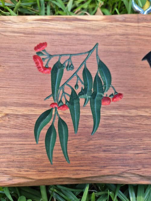wood sign with coloured gumleaves and flowers engraved in spotted gum