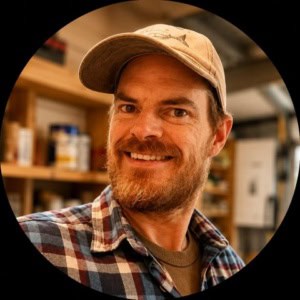 Profile photo of woodworker Andrew Wilkerson in his workshop with cap on his head.