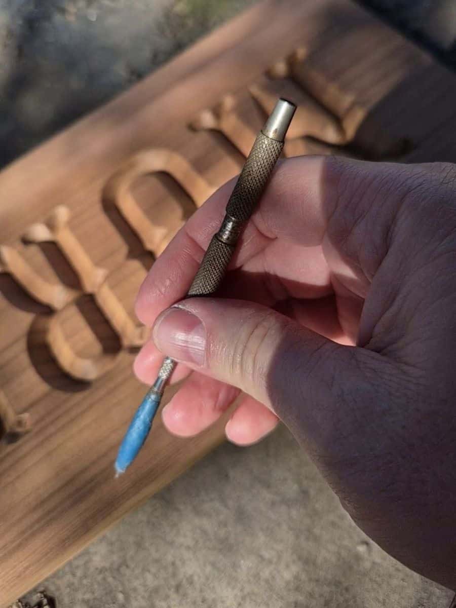 Close-up of a modified scribe used to clean burrs and loose wood fibres from carved wooden lettering.