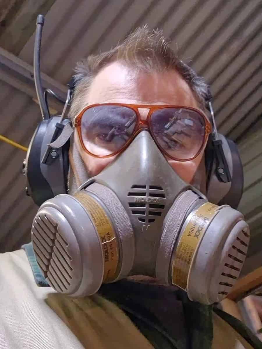 Woodworker wearing safety glasses, hearing protection and a respirator in the workshop.